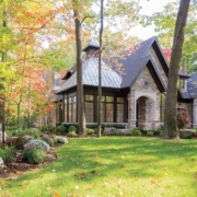 Traditional home design with natural stone, dark brown trim and large windows.